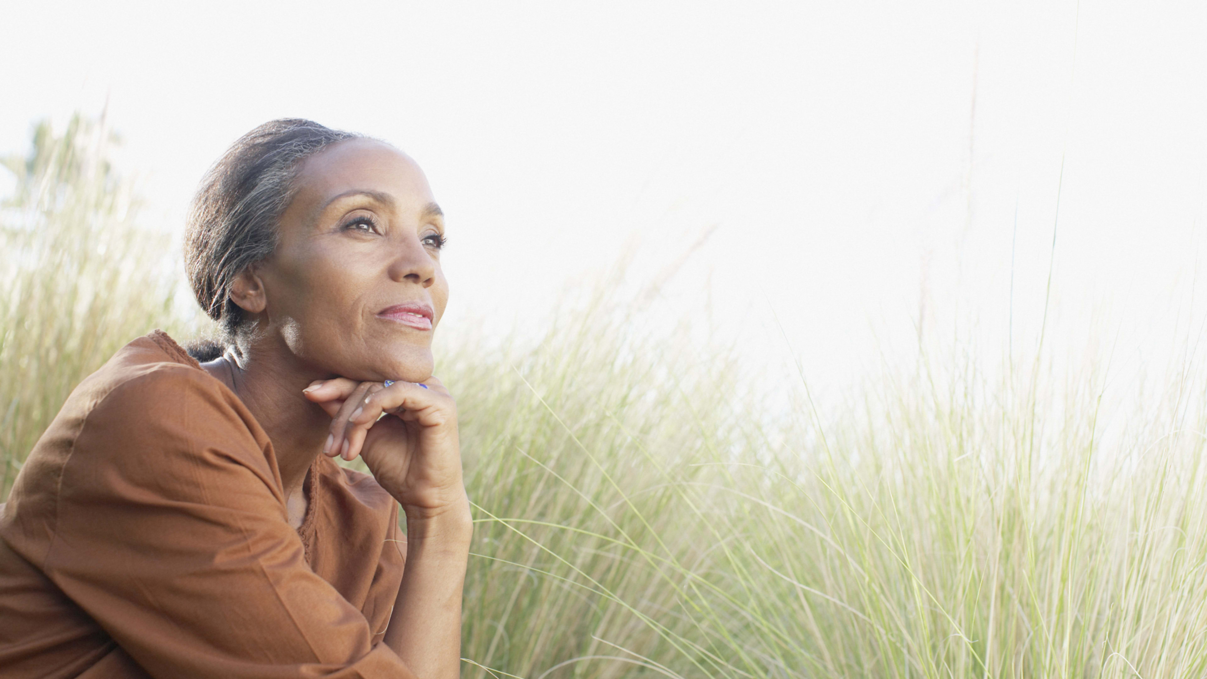 Serene woman sitting in sunny field